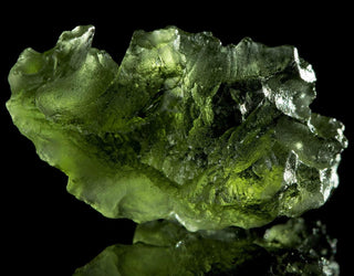Glowing green Moldavite crystal with rugged, glassy texture and cosmic patterns