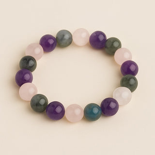 A digital photograph features a beaded stretch bracelet arranged in a circle, alternating rose quartz, amethyst, and labradorite beads, set against a neutral beige background.