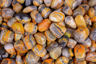 Bright yellow-and-orange banded Bumblebee Jasper crystal on a dark background